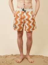 Short de baño tipo volley con estampado de ondas en tonos naranja y beige. Presenta cintura elástica en color contraste con cordón de ajuste y detalle de bordado en la pierna derecha.