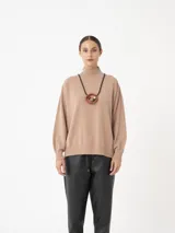 Sweater color beige de viscosa y poliéster, con cuello alto, puños largos y mangas amplias con puño alto.