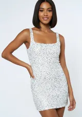 Vestido corto ajustado cubierto de lentejuelas plateadas, con escote cuadrado y breteles anchos.