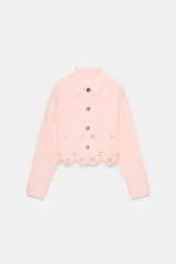 Cazadora color rosa pálido, de cuello solapa y manga larga. Tiene bordados perforados a tono en el ruedo y cierre frontal con botones color madera.