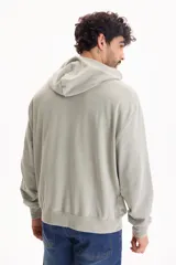 Campera con capucha y cierre frontal, color beige con efecto lavado stone wash, bolsillos tipo canguro y corte oversize.