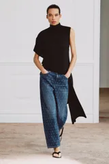 Jeans de tiro medio con corte tapered y largo al tobillo. Presenta un diseño de cinco bolsillos, cierre frontal con cremallera y botón, y un estampado de lunares a contraste sobre un tejido denim con efecto lavado.