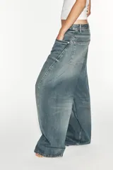 Jeans de tiro medio y corte baggy oversize con diseño de costuras marcadas en las piernas, trabillas para cinturón y cinco bolsillos tradicionales. Cierre frontal con cremallera y botón metálico.