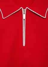 Jersey de punto fino color rojo con cuello polo y cierre frontal. Presenta ribetes en contraste color blanco en el cuello y en los bordes de las mangas cortas.