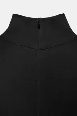 Mono largo negro con cuello subido y manga larga ajustada. El cuerpo superior es liso y ajustado, mientras que la parte inferior es de pantalón ancho con mucho volumen y frunces, ajustado en el tobillo con una lazada.