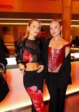 Conjunto de dos piezas compuesto por un top corto sin mangas de cuello redondo y una falda midi, ambos confeccionados en tejido de malla transparente color negro con estampado floral en tonos rojos.