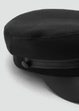 Gorro estilo baker boy de color negro, con diseño rígido y visera combinada en material sintético.