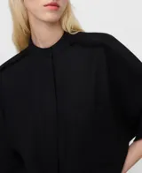 Camisa negra oversize de lino y viscosa, con cuello mao, botonadura frontal oculta por sopata, manga murciélago con vuelta bajo el codo, bolsillo en el pecho y costuras desflecadas en el canesú y las mangas.