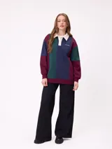 Sweater estilo rugby de Rusty, con diseño color block en tonos bordó, azul marino y verde. Presenta cuello polo en color crema con cierre frontal de botones, mangas largas con puños elásticos y logo de la marca bordado en el pecho.