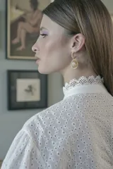 Aros colgantes dorados con medio aro superior texturizado y piedra redonda color crema.