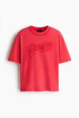 Remera de algodón en punto pesado, color rojo con efecto lavado, cuello redondo acanalado, hombros caídos y estampa frontal con relieve que dice 'Sunset'.