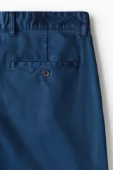 Pantalón de sarga de algodón en color azul marino, con corte relajado, cierre de cremallera y botón, bolsillos laterales al bies y bolsillos traseros insertados con botón.