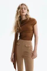 Pantalón acampanado de punto roma en color tostado, con cintura elástica oculta y solapas de bolsillo decorativas con botones dorados en la parte frontal.