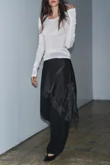 Falda corta de tiro medio confeccionada en tejido satinado negro, con bajo asimétrico y aplicación de encaje a tono.