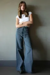 Jean de pierna ancha color gris oscuro, con cintura alta, bolsillos delanteros y traseros con detalle de trenzado, y cinturón de soga.