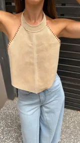 Top halter color beige, estilo chaleco corto, con cuello alto y bordes festoneados con costura decorativa.