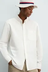 Camisa de algodón color blanco hueso, de corte regular, con cuello abotonado, manga larga terminada en puño con botón y bolsillo de parche en el pecho.