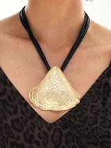 Collar dorado con colgante circular con diseño abstracto y textura labrada. El collar es de cordón negro.