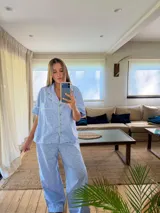 Pijama de dos piezas, compuesto por una camisa de manga corta y pantalón largo, ambos con estampado floral pequeño en tonos azules y blancos, y ribetes de color claro en los bordes.