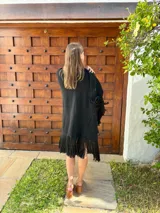 Ruana tejida en lana, de color negro, con diseño de flecos en los bordes inferiores.