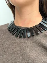 Collar corto de obsidiana natural con piezas rectangulares negras, cadena de extensión dorada y dije colgante de piedra.