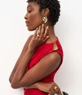 Vestido midi sin mangas color rojo, confeccionado en microfibra con elastano. Presenta un diseño drapeado en el lateral de la cintura con un adorno metálico en forma de gota, escote redondo y una abertura lateral en la falda.