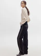 Pantalón de pana roja con corte holgado y tiro medio. Presenta una línea dorada a lo largo de la pierna.