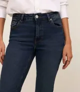 Pantalón de jean corte bootcut, color negro, con tiro alto, trabillas en la cintura, cierre de botón y bolsillo reloj.