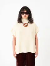 Chaleco tipo poncho de tejido grueso con cuello alto tipo polera, diseño holgado y hombros caídos. Confeccionado en una mezcla de lana y fibras sintéticas que aportan suavidad y abrigo.