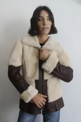 Campera reversible confeccionada en napalán de cuero genuino, con diseño de paneles en color marrón oscuro y crema. Presenta cierre frontal, cuello solapa y puños con detalle de piel a la vista.