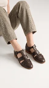 Sandalias tipo cangrejera de cuero color marrón, con diseño de tiras cruzadas y textura en la parte frontal. Cuentan con pulsera al tobillo con hebilla metálica y taco bajo.
