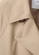 Gabardina larga color beige, de doble botonadura, con solapas amplias, mangas largas raglán, cinturón ajustable con hebilla y bolsillos laterales.