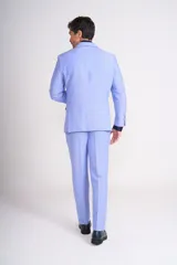 Traje de lino color beige claro, compuesto por saco de dos botones con solapa de muesca, dos bolsillos delanteros con solapa y un bolsillo en el pecho, y pantalón de vestir de corte recto. Incluye camisa blanca, corbata estampada y zapatos marrones.