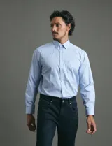 Camisa de vestir de manga larga con diseño de rayas verticales finas en color celeste y blanco. Presenta cuello clásico, cierre frontal con botones y un bolsillo en el pecho.