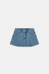 Falda corta de tiro medio confeccionada en tejido denim de algodón. Presenta diseño con tablas, bolsillos delanteros, cintura con trabillas y bajo desflecado. Cierre frontal con cremallera, botón y ganchos metálicos.