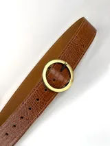 Cinturón de cuero con textura de reptil en color marrón, con hebilla circular metálica en tono dorado envejecido.