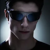 Lentes de sol envolventes con montura de acero inoxidable en acabado plateado cepillado y lentes de nylon espejadas. Presentan un diseño vanguardista con aberturas decorativas en la parte superior del marco.