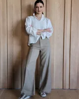 Pantalón de jean color beige, de corte recto y tiro alto, con costuras verticales decorativas en el frente y ruedo deshilachado.