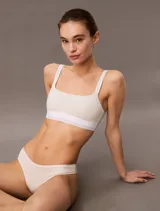 Corpiño deportivo Calvin Klein Icon Modal Mesh, color blanco roto, con tirantes anchos y banda elástica inferior con logo repetido.