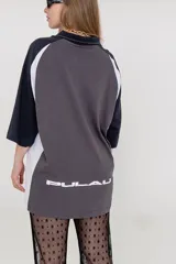 Pantalón acampanado de encaje negro, con estampado de pequeñas flores en relieve. El tejido es semitransparente y cae sobre un calzado tipo zueco negro.