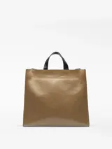 Bolso shopper de estructura cuadrada en color marrón con acabado brillante y textura craquelada. Cuenta con asas de mano y asa larga para hombro en color negro, cierre de solapa interior con cremallera y bolsillo interior. Logo grabado en la parte frontal.