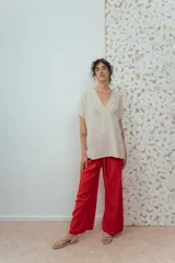 Blusa de lino color beige de calce relajado, con escote en V y detalles de pliegues frontales. Posee mangas cortas y una silueta suelta.