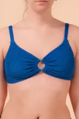 Top de bikini azul con textura y aro metálico en el centro.