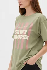 Remera de algodón color beige con estampado frontal de un corazón rosado que contiene un moño. Tiene cuello redondo y mangas cortas.