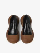 Mocasín de cuero vacuno color negro con diseño híbrido y suela voluminosa de aspecto amaderado.