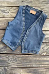 Chaleco negro de cuero con escote en V y cierre frontal con cordones. Presenta ojalillos metálicos plateados a lo largo de los bordes.