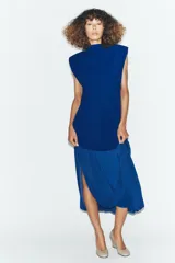 Vestido midi de color azul eléctrico con cuello subido y diseño sin mangas. Presenta un cuerpo liso y una falda con caída fluida y detalle de tul en el bajo.