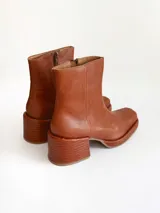 Bota de caña media color óxido, confeccionada en cuero, con plataforma y taco cuadrado texturizado, punta cuadrada y cierre lateral.