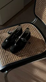 Ballerinas negras de tela, con tiras tipo cinta con hebilla entrelazadas en la capellada. El fondo es de suela, forradas en forrería vacuna y los detalles son de cuero.