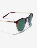 Lentes de sol Hawkers unisex, modelo Ollie. Marco de carey con borde inferior transparente, lentes verdes y patillas doradas.